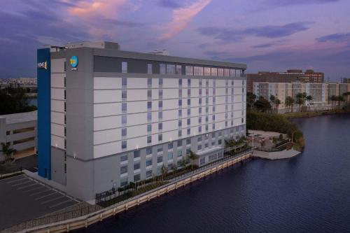 a large white building next to a body of water at Tru By Hilton Miami Airport South Blue Lagoon, Fl in Miami