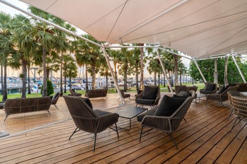 un patio con sillas y mesas en una terraza de madera en Ocean Marina Resort Pattaya Jomtien, en Na Jomtien