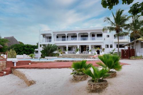 un grand bâtiment blanc avec des palmiers devant lui dans l'établissement Met Beach Resort Malindi, à Malindi