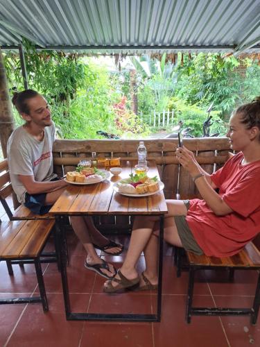 a man and woman sitting at a table with food at Homestay field - bungalow, Ha giang loop tour, motorbikes rental in Ha Giang