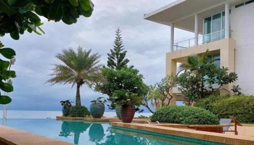 uma piscina em frente a um edifício com palmeiras em Karon Sea View Beach Apartment em Praia de Karon