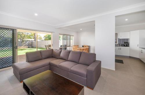 ein Wohnzimmer mit einem braunen Sofa und einer Küche in der Unterkunft Large house 7 mins from Airport in Brisbane