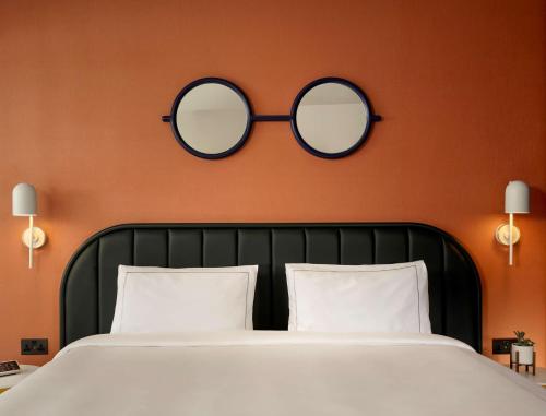 um quarto com uma cama com dois espelhos na parede em art'otel London Battersea Power Station, Powered by Radisson Hotels em Londres