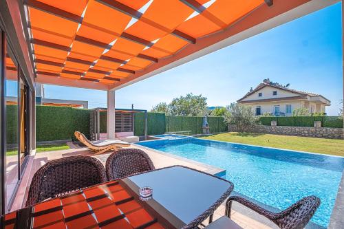 eine Terrasse mit einem Tisch und Stühlen sowie einem Pool in der Unterkunft luxurylifevillas 1-2-3-4 in Fethiye