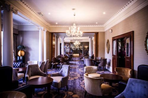 チェルトナムにあるDoubleTree by Hilton Cheltenham-Cotswoldsの椅子とテーブル、シャンデリアのあるレストラン