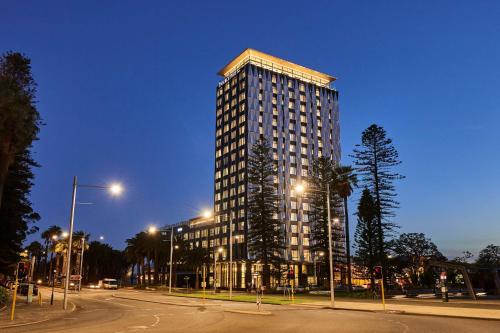 珀斯Doubletree By Hilton Perth Waterfront的夜幕降临的城市街道上一座高楼