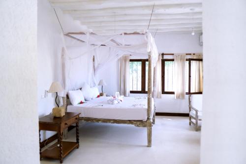 - une chambre avec un lit blanc à baldaquin dans l'établissement Met Beach Resort Malindi, à Malindi