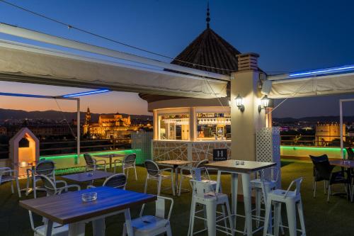 un patio en la azotea con mesas y sillas por la noche en Hesperia Córdoba, en Córdoba