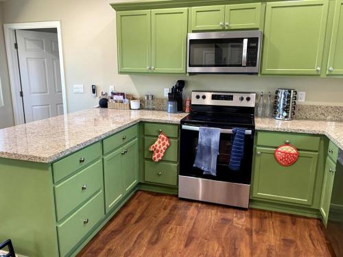 a green kitchen with a stove and a microwave at Walnut Cottage in Badger