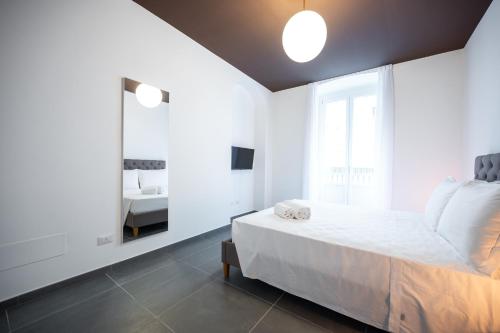 een witte slaapkamer met een bed en een spiegel bij Porta Nuova Luxury Apartments in Turijn