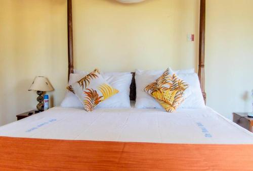 1 dormitorio con 1 cama grande con sábanas y almohadas blancas en Sand and Shells Beach House- 4 Bedroom with a pool, en Mombasa