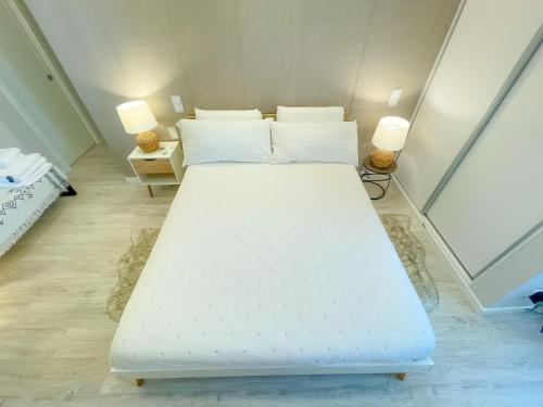 a large white bed in a room with two lamps at Airport Lisbon Guest House in Lisbon