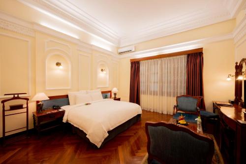 a hotel room with a bed and a desk and chairs at Hotel Majestic Saigon in Ho Chi Minh City