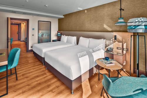 um quarto com uma cama grande, uma mesa e cadeiras em Doubletree By Hilton Antalya City Centre em Antália