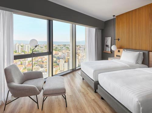 um quarto de hotel com duas camas e uma cadeira em AC Hotel by Marriott Split em Split