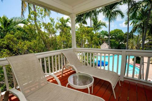 un portico con due sedie e un tavolo e una piscina di Coral Hammock Poolside Home a Key West