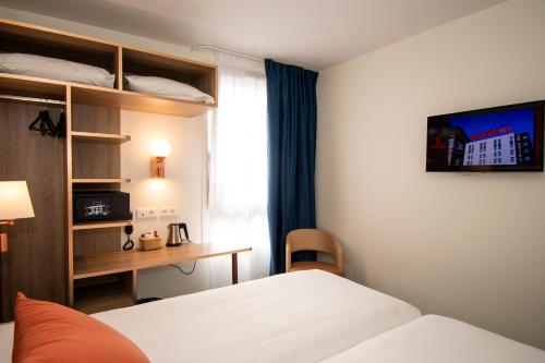 a hotel room with a bed and a desk and a television at K Hotel in Strasbourg