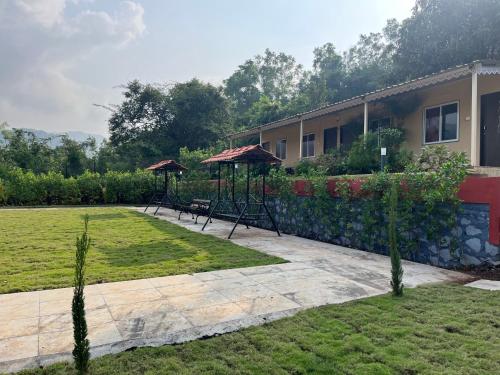 un jardin avec deux balançoires et des parasols en face d'une maison dans l'établissement VRISA Mountain Retreat, à Pune