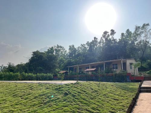 un bâtiment avec une pelouse devant lui dans l'établissement VRISA Mountain Retreat, à Pune