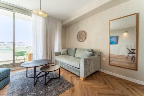 uma sala de estar com um sofá, uma mesa e um espelho em Luxury Apartments - By Harim em Eilat