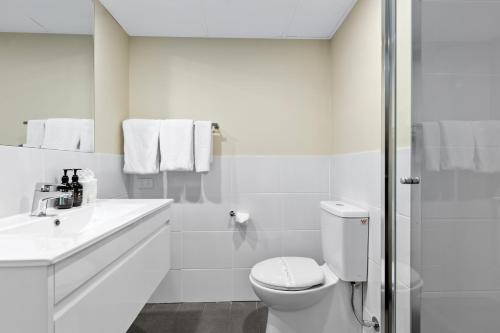 a white bathroom with a toilet and a sink at Econo Lodge North Adelaide in Adelaide