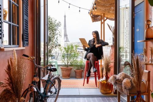 a woman sitting on a chair in a room with the eiffel tower at Quinzerie hôtel in Paris