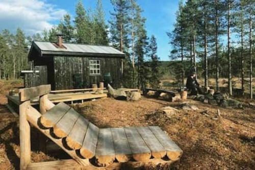 una panchina di legno seduta di fronte a una cabina di Velkommen til Finnskogen og minihytta Rimbila a Kongsvinger