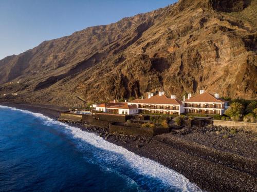 a house on the side of a mountain next to the water at Parador de El Hierro in Las Casas