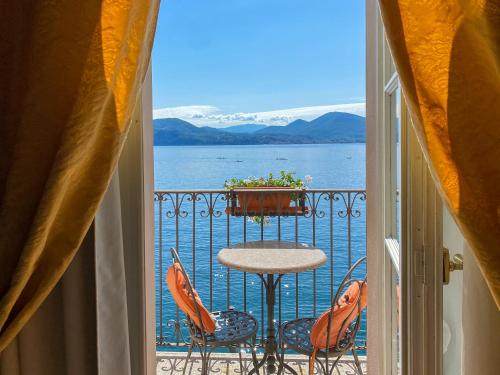 een balkon met een tafel en stoelen en uitzicht op het water bij Hotel Cannero in Cannero Riviera