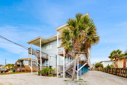 a house with a palm tree in front of it at Okaloosa Island Studio in Fort Walton Beach