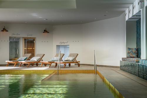 una piscina de agua en una habitación con bancos en Harbour Beach Club, Hotel & Spa en Salcombe