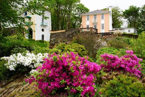 uma casa numa colina com flores à sua frente em Portmeirion Village & Castell Deudraeth em Porthmadog