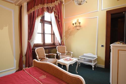 a bedroom with a bed and chairs and a window at Hotel Leopold I in Novi Sad