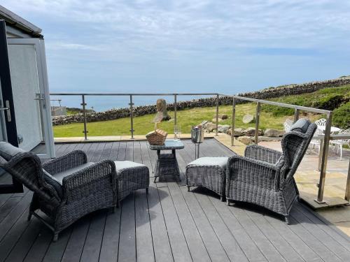 taras z 2 krzesłami i stołem z widokiem na ocean w obiekcie Goferydd, South Stack, Anglesey, 4 bed luxury home, hot tub, dog friendly w mieście Holyhead