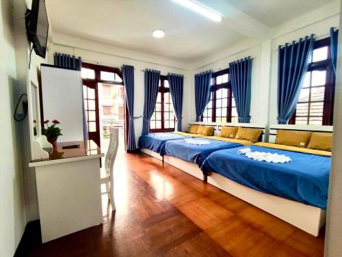 - une chambre avec un lit doté de draps bleus et de fenêtres dans l'établissement Dona Dalat Hotel, à Đà Lạt