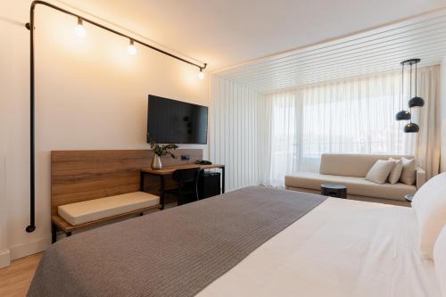 1 dormitorio con 1 cama, TV y sofá en Magnolia Hotel - Adults Only, en Salou