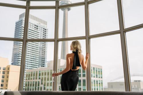 uma mulher a olhar pela janela para uma cidade em SoHo Hotel Toronto em Toronto