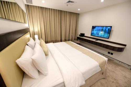 a bedroom with a large white bed and a flat screen tv at Carlton Tower Hotel Kuwait in Kuwait