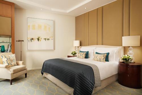 a bedroom with a large bed and a chair at Corinthia London in London