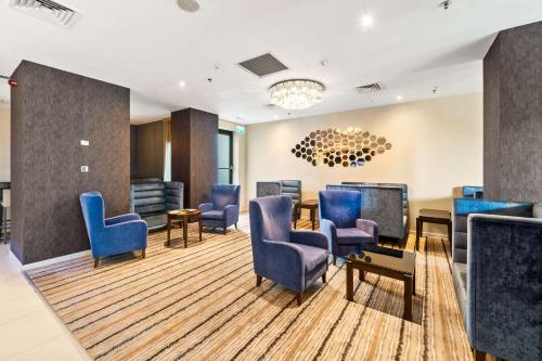 a waiting room with blue chairs and a tv at Hampton by Hilton Cluj-Napoca in Cluj-Napoca