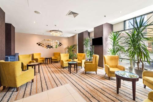 a waiting room with yellow chairs and tables at Hampton by Hilton Cluj-Napoca in Cluj-Napoca