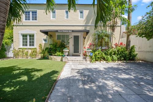 a house with a palm tree in front of a driveway at villa venezia bb in Miami Beach