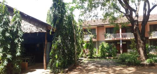 un edificio con árboles delante de él en PRIMESHADE GUESTHOUSE, en Malindi