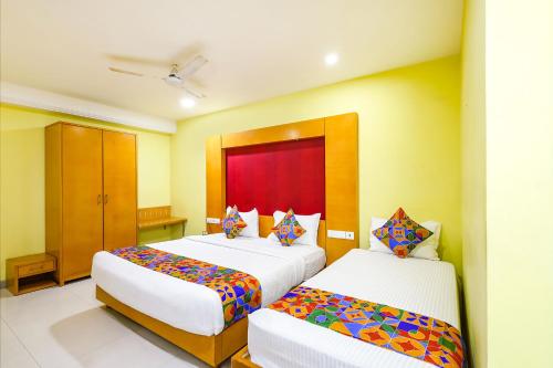 um quarto de hotel com duas camas com almofadas coloridas em FabHotel Prime Mahalaya Residency - Nr The Rajiv Gandhi Memorial & PVR Grand Galada em Chennai