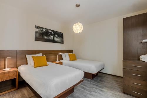 two beds in a hotel room with yellow pillows at OM 686 URBAN LOFTS Narvarte in Mexico City