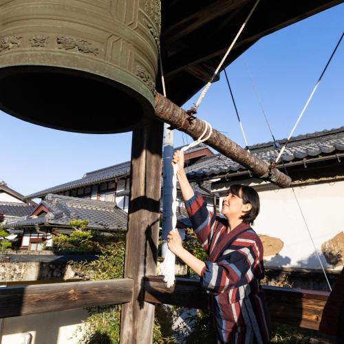 Eine Frau klettert auf eine Glocke in der Unterkunft 湖北 寺の宿-去-来-現Ko-Rai-Gen in Nagahama