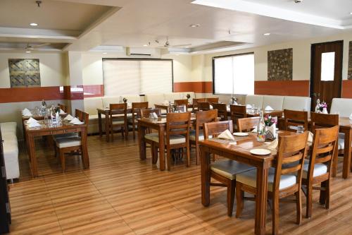 a dining room with wooden tables and chairs at Sai Neem Tree Hotel in Shirdi