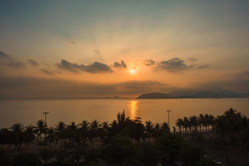 un coucher de soleil sur une étendue d'eau bordée de palmiers dans l'établissement Bluebay Hotel, à Nha Trang