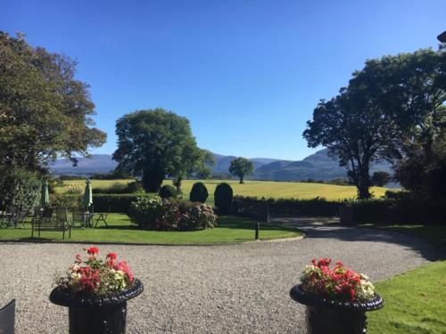 um jardim com flores em vasos numa estrada de cascalho em Loch Lein Country House em Killarney