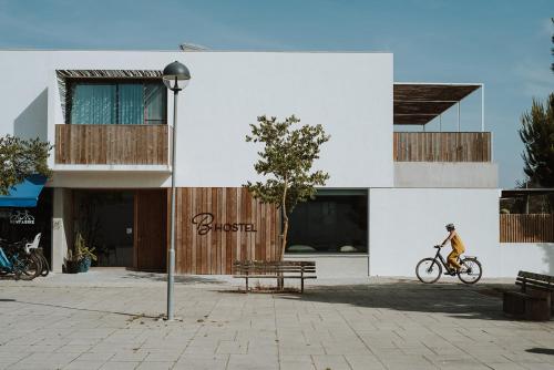 uma pessoa a andar de bicicleta em frente a um edifício em B.Hostel na Comporta